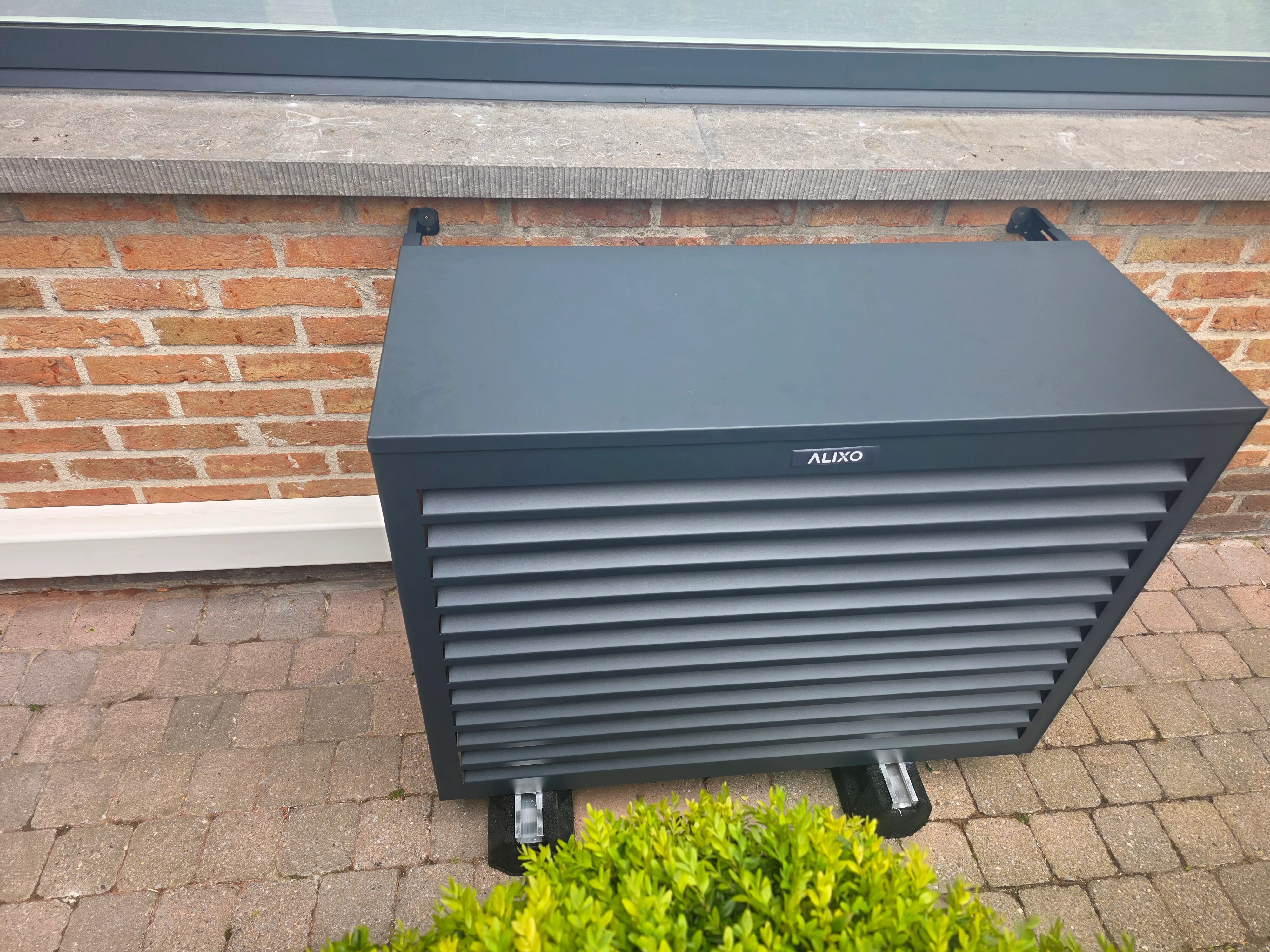 Buitenunit van een warmtepomp naast een woning